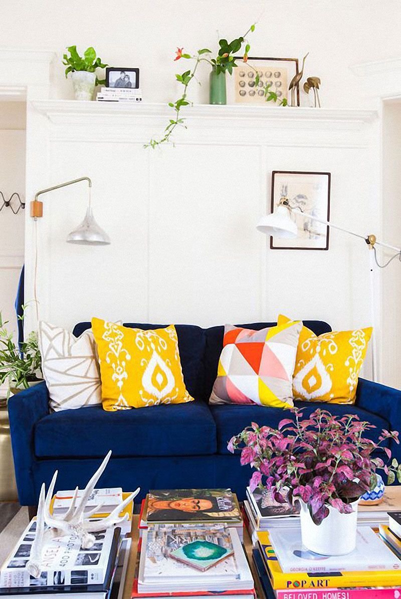 Синий диван с желтыми подушками в интерьере